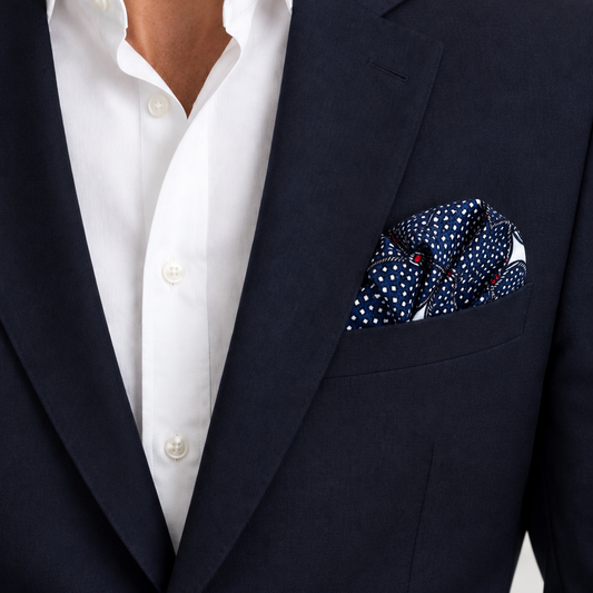 Navy pocket square with a dotty pattern and red accents worn in man's suit pocket