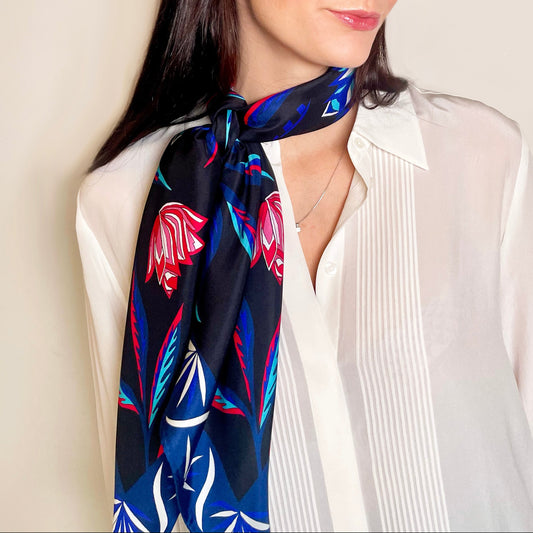 A woman wearing a black scarf with a bright blue and red floral design.