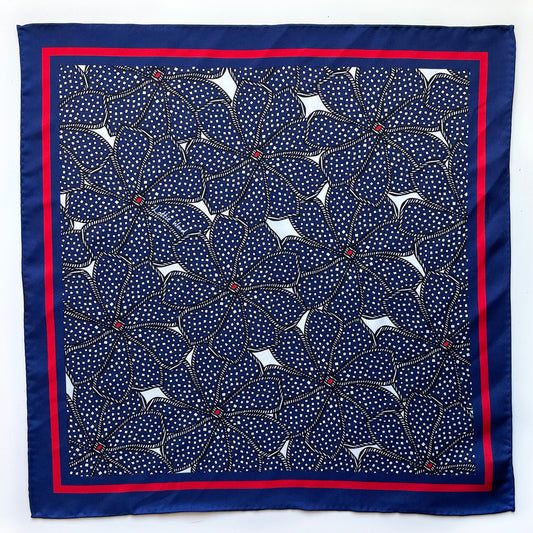 Navy dotty silk pocket square shown lying flat with a playful navy and red dot print on a white background.